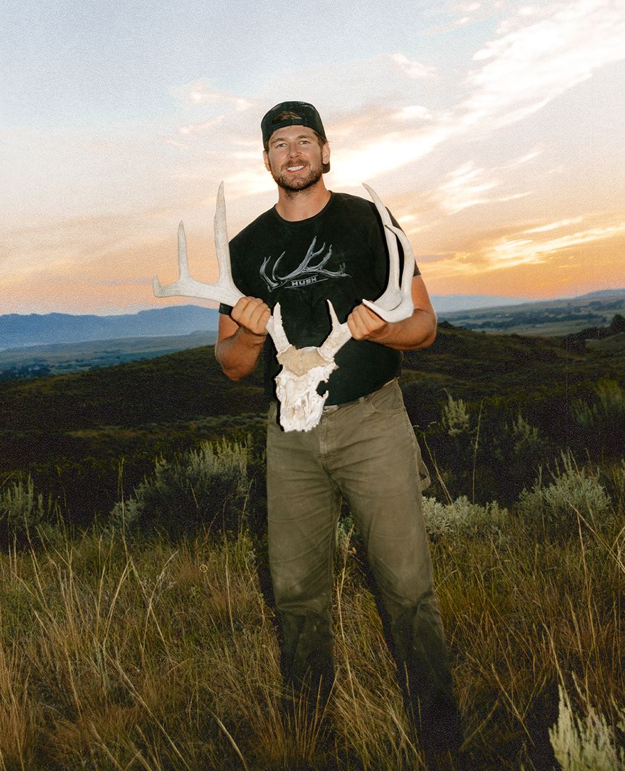 Jonah holding a mule deer skull and antlers at sunset on a sagebrush ridge